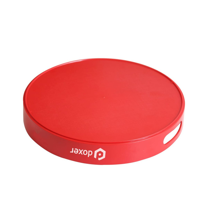 A round red serving tray with a textured surface and a side handle, featuring a logo.