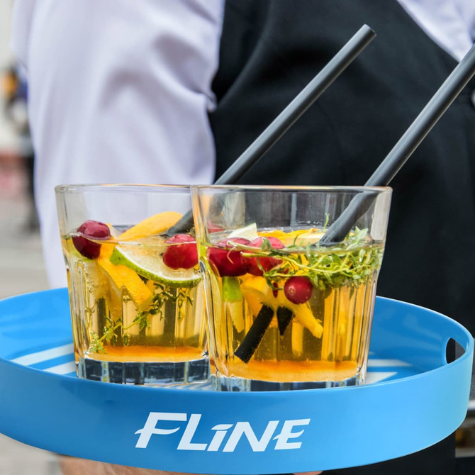 A blue bar serving tray with two glasses containing colourful cocktails garnished with citrus and herbs.