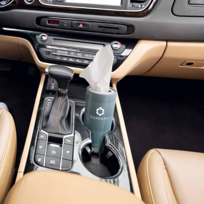 A car cup tissue holder in teal, situated in a vehicle's centre console, with a tissue partially visible inside.