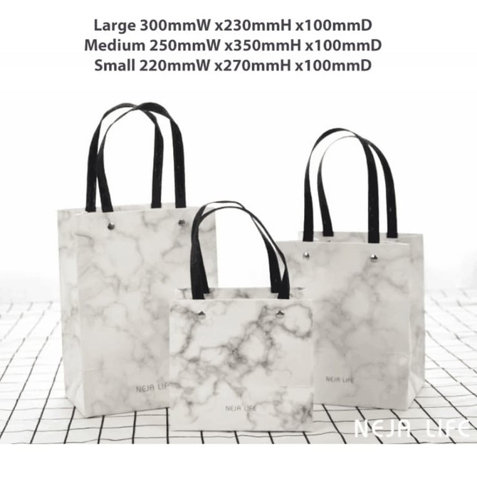 A set of three marble-patterned bags with black handles, in large, medium, and small sizes, featuring one logo.