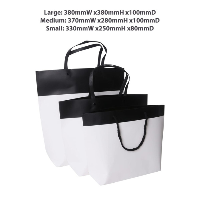 Medium black and white boutique paper bag with sturdy handles, featuring a sleek design. Contains a logo.