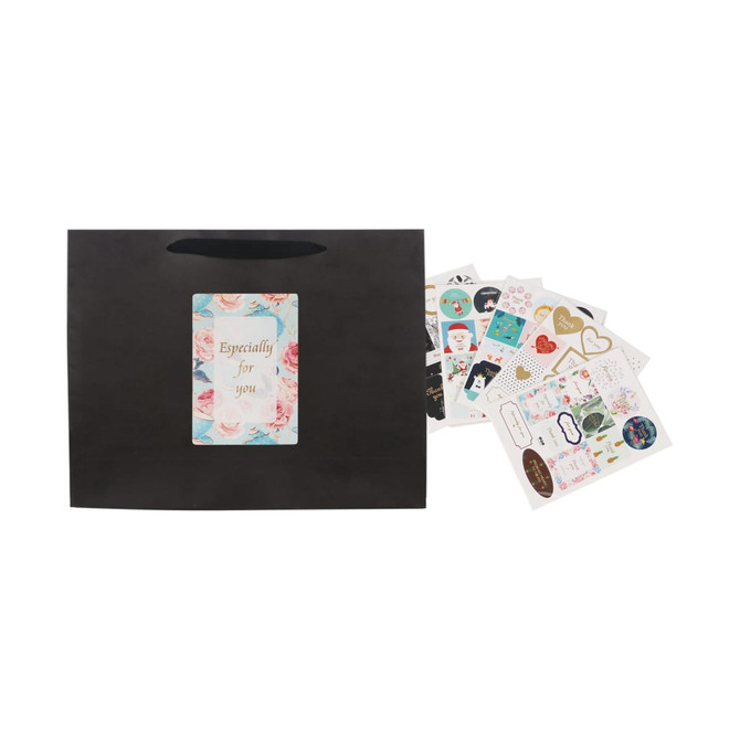 A large black paper bag with a fabric handle, accompanied by various decorative stickers.