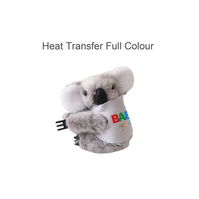 A plush koala toy with grey fur, holding a small black object, featuring a logo on a white shirt.