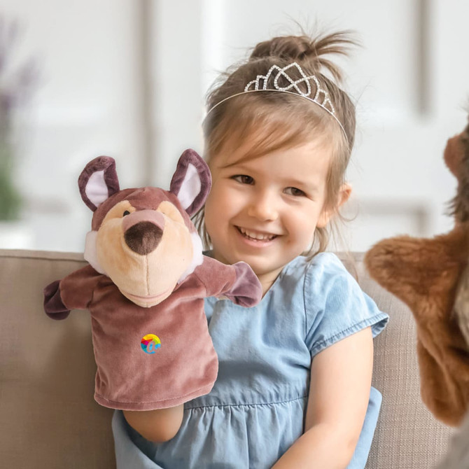 A plush wolf hand puppet in brown and beige, held by a smiling child sitting on a couch.