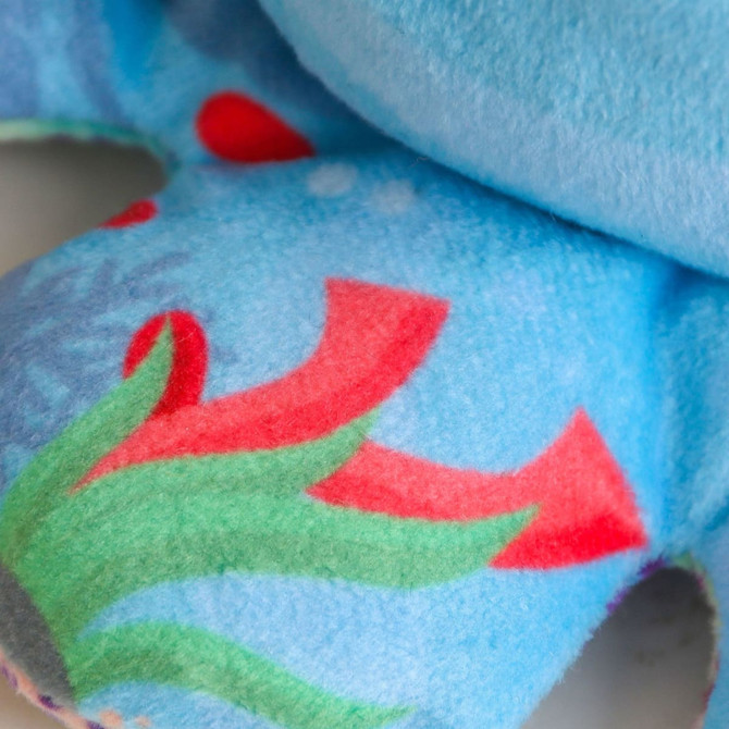 A blue keyring featuring a plush animal design with colourful patterns of red and green elements.