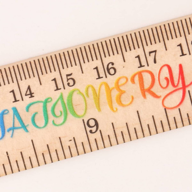A wooden ruler featuring a dual scale and a colourful gradient design. It has a logo present on the surface.