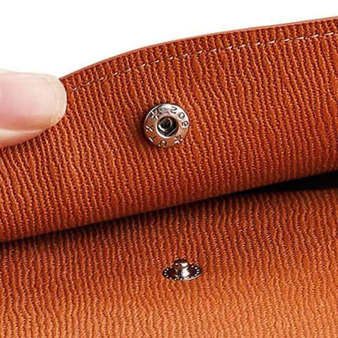 A close-up of an orange PU leather A4 file bag, highlighting its textured surface and snap closure.