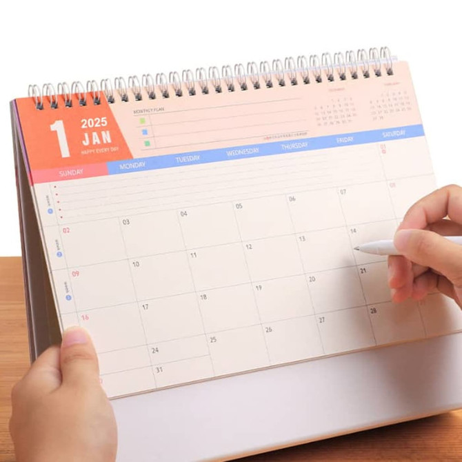 A desk calendar featuring a spiral binding with a colourful top section and a blank monthly layout for January 2025.