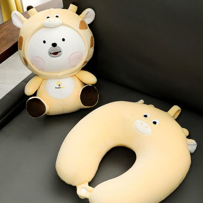 A plush giraffe-shaped travel pillow in light yellow, accompanied by a matching sitting animal toy.