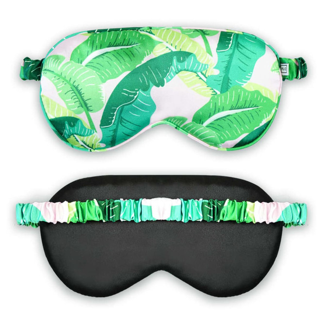 A satin sleep mask featuring a vibrant green leaf pattern on one side and a solid black reverse with a decorative band.