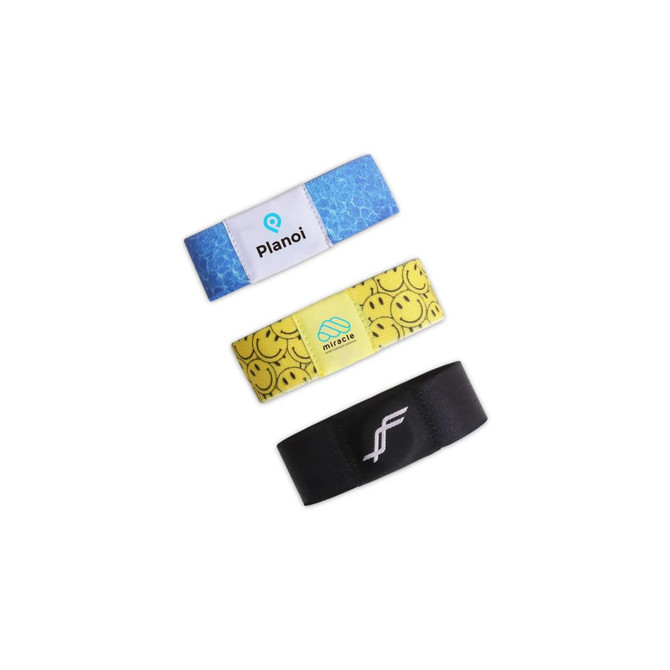Three stretchy wristbands in blue, yellow with smiley faces, and black, each featuring a logo or branding.