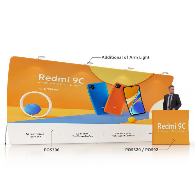 A large U-shaped tension fabric display wall featuring orange and blue colours, with a promotional stand and a person beside it.