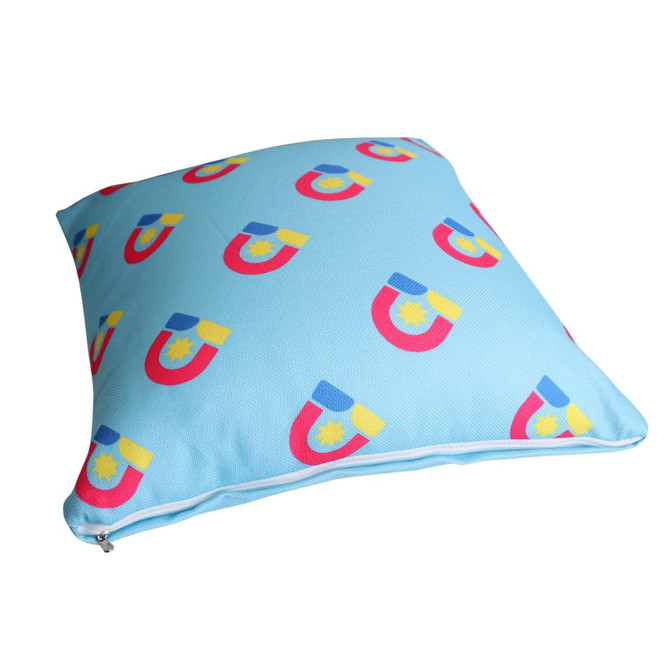 A square cushion featuring a light blue background with colourful magnet patterns. It has a zip closure and a logo.