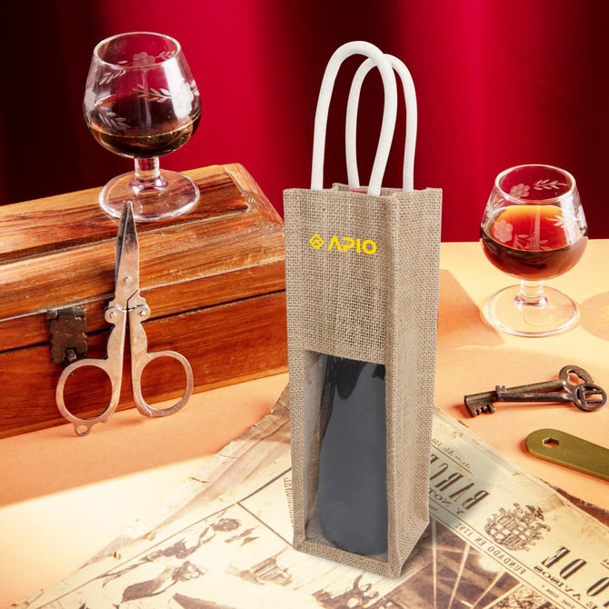 A jute wine carrier in natural colour with a window, featuring two handles and a logo, displayed on a vintage table setting.
