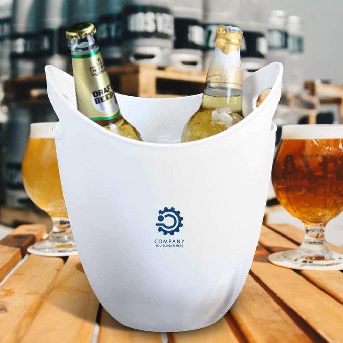 A white ice bucket containing two bottles of beer, placed on a wooden surface with beer glasses in the background.