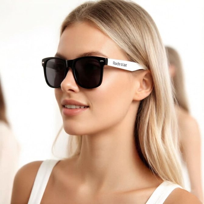 Stylish black sunglasses with white arms, featuring a logo, worn by a woman with long blonde hair.