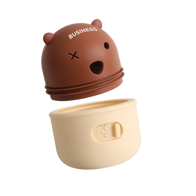 A brown and cream dog treat dispenser toy, featuring a bear-shaped lid with a logo and an internal compartment for treats.