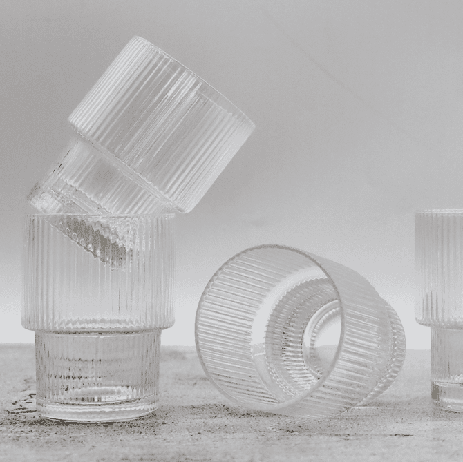 A set of clear ribbed glass tumblers stacked in a creative arrangement. Each tumbler features a textured design.