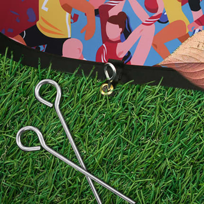 Oval-shaped pop-up banner featuring vibrant graphics, set on green grass with metal pegs beside it.