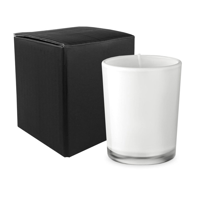 A glass candle in a clear container next to a black box. The candle is white and has a simple design.