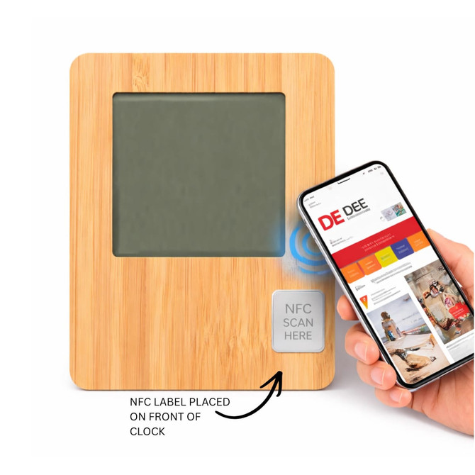 A bamboo desk clock featuring a grey display, with an NFC label and a hand holding a smartphone nearby.