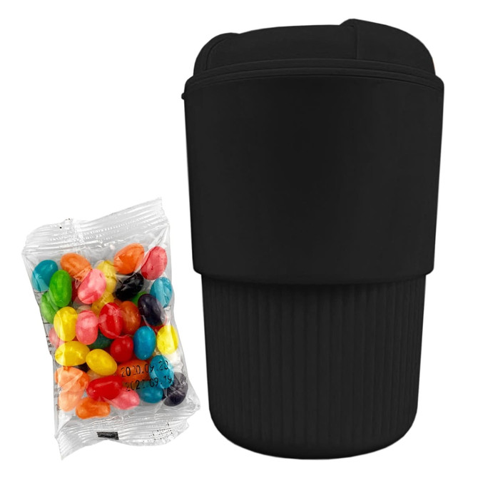 A reusable black coffee cup with a ribbed design beside a pack of colourful jelly beans, featuring a logo.