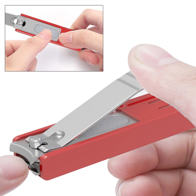 A red nail clipper with a stainless steel blade and a keyring attachment, being held by a person's hand.