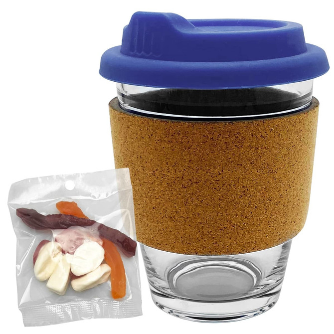 A glass coffee cup with a cork band and blue lid, accompanied by a bag of mixed lollies in various colours.