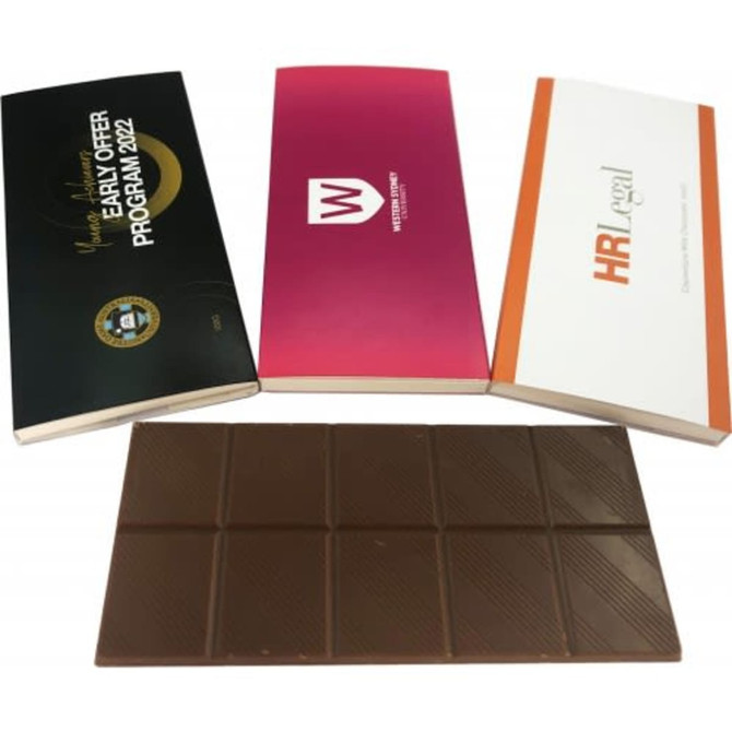 A brown 100g chocolate bar is displayed alongside two promotional boxes with different designs and logos.