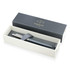 A matte grey ballpoint pen displayed in a white box with a black interior, featuring a logo.