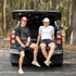 Two young men sitting on the tailgate of a truck, wearing a red and white Turbine Trucker Cap and a white cap.