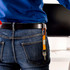 A carabiner keyring in orange attached to a black belt loop, holding keys. A person in blue and denim is visible.