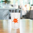 A translucent plastic stadium cup in clear colour with an orange splash logo, positioned on a wooden table.