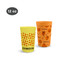 Two 355ml plastic stadium cups, one yellow with a patterned design and one orange featuring a playful print.
