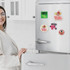 A fridge covered with colourful acrylic magnets depicting various designs, alongside a person interacting with the fridge.