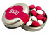 A silver tin container with a lid, filled with red and white chocolate-coated beans and featuring a logo.