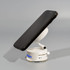 A white vacuum suction magnetic phone stand holding a black smartphone, featuring a circular base and adjustable arm.