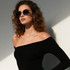 Classic metal sunglasses in black, worn by a model with curly hair, against a light background.