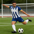 A model wears blue and white striped breathable soccer shorts, kicking a black and white soccer ball on a field.