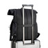 A black polyurethane roll top backpack resting on a suitcase with an extended handle, showcasing its design and features.