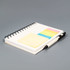A spiral-bound notebook with blank pages, accompanied by yellow, pink, and green sticky notes and a black pen.