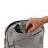 A grey business sling laptop bag with a hand reaching into an outer pocket. It features a sleek design and a logo.