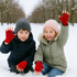 Red fingerless gloves worn by children, smiling and raising their hands, set in a snowy outdoor environment.