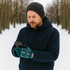 Adults Jacquard Gloves in teal with patterned cuff, worn by a man in a beanie, using a smartphone in a snowy landscape.