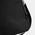 A black duffle bag with a subtle texture and an attachment point for a strap, featuring a small logo.