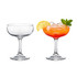 A set of clear glass martini coupe glasses, one empty and the other filled with a colourful drink and garnished with lemon and mint.
