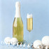 A champagne bottle with a white foil top beside a straight champagne flute filled with sparkling wine, set on a light blue background.