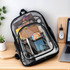 A transparent backpack featuring black edges, filled with various items including stationery and a cute character keychain.