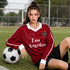 A unisex red football jersey featuring white accents, worn by a model seated beside a soccer ball.