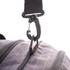 A close-up of a black clip and strap attachment on a grey duffle bag. The bag features zippers and textured fabric.